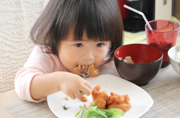唐揚げを食べる小さな女の子の写真